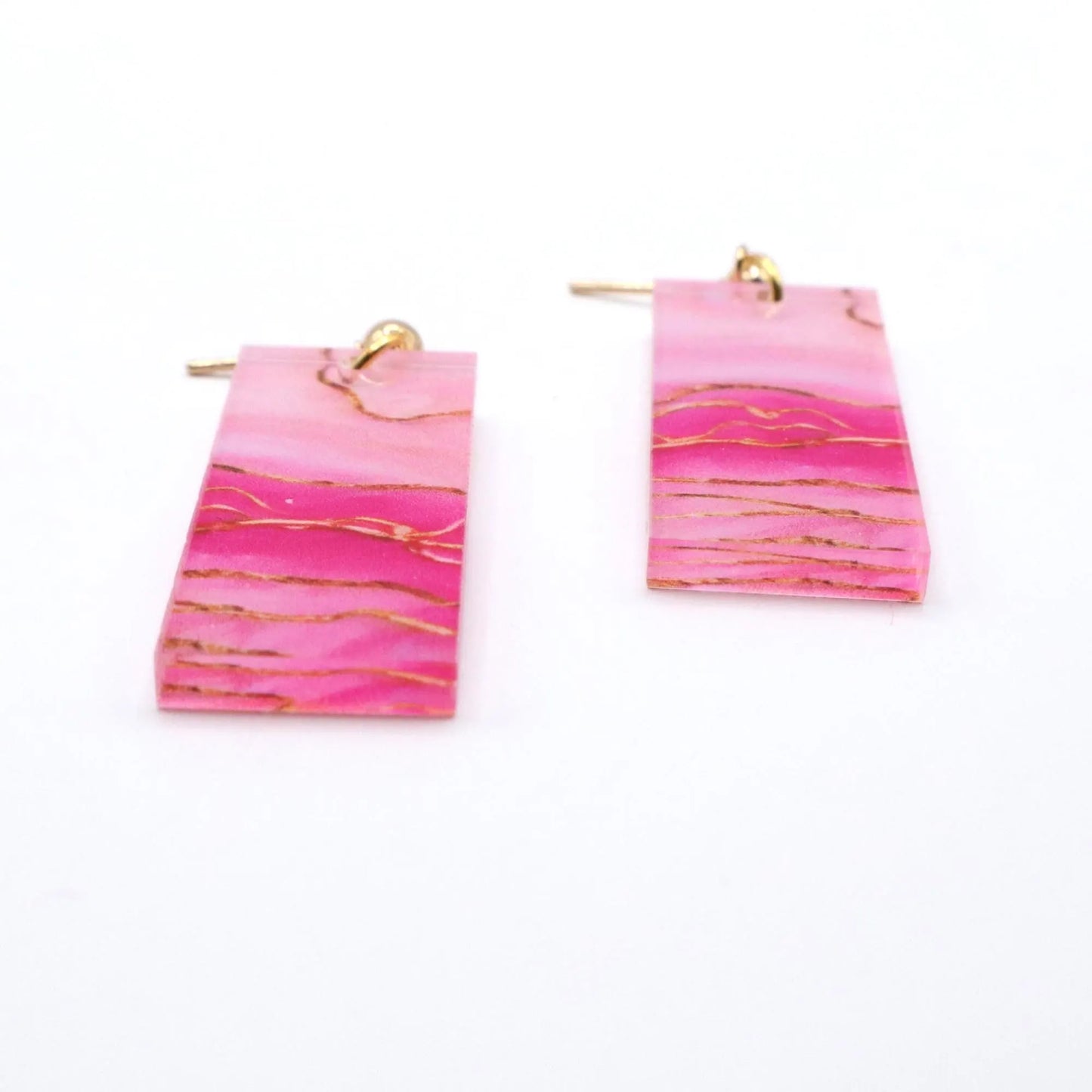 Pink earrings with gold accents on a white background