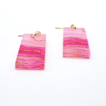 Pink earrings with gold accents on a white background