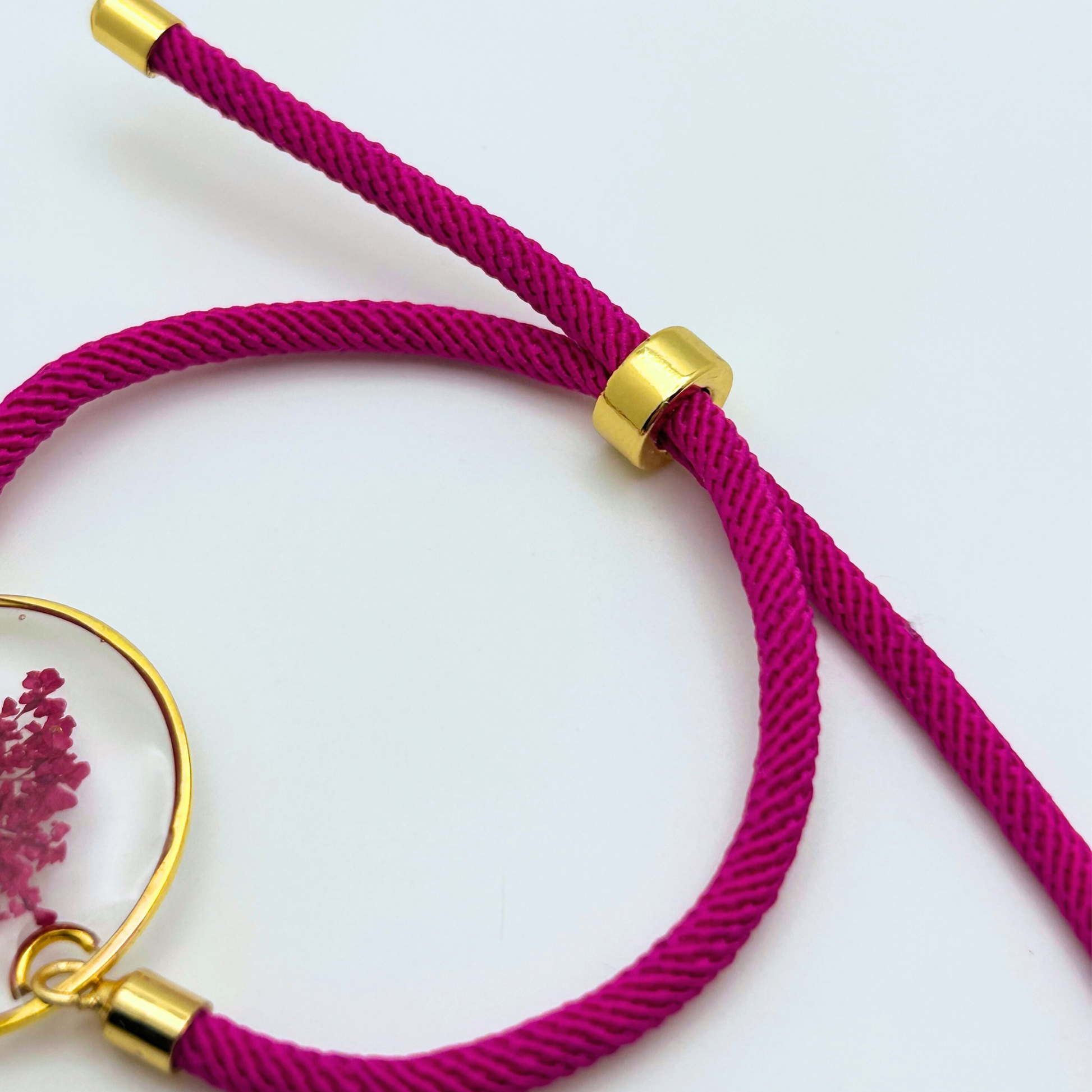 Close-up of adjustable magenta cord bracelet with gold slider and hardware detail