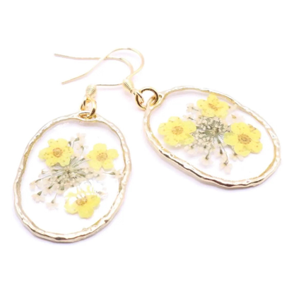 Handmade resin earrings featuring pressed yellow flowers and delicate white florals in clear oval setting with gold edge and hook ear wires