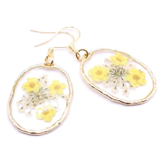 Handmade resin earrings featuring pressed yellow flowers and delicate white florals in clear oval setting with gold edge and hook ear wires