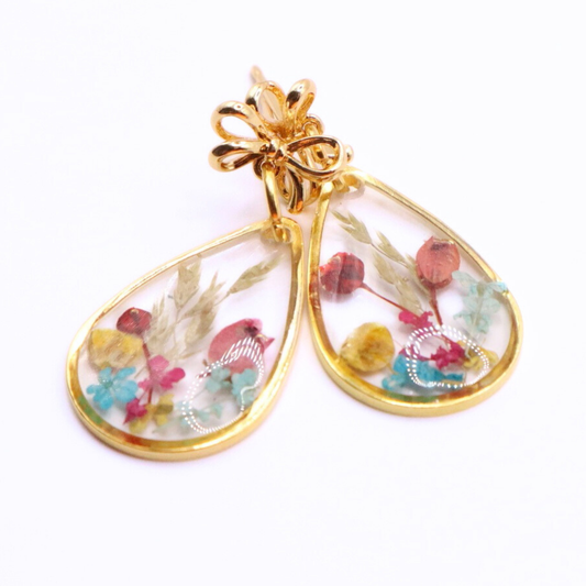 Gold-framed earrings with colorful floral design on a white background